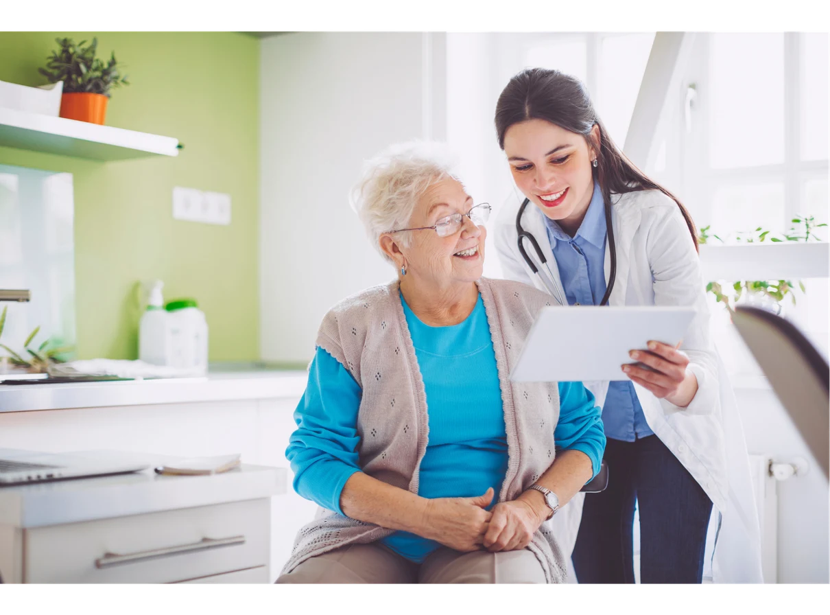 Doctor reviewing a tablet with an elderly patient in a bright medical setting.